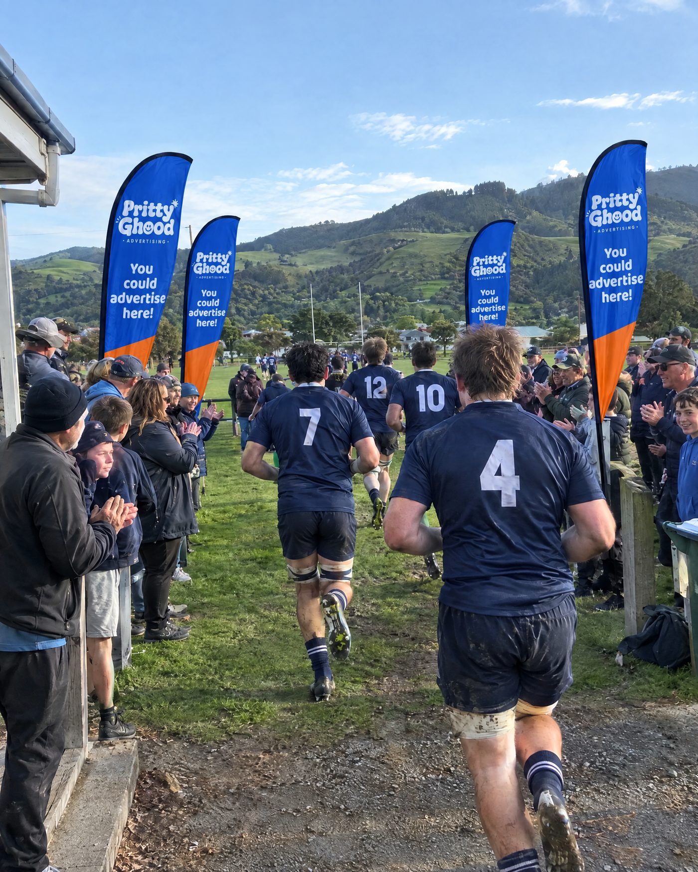 A rugby team running out between rows of Pritty Ghood teardrop flags and cheering supporters