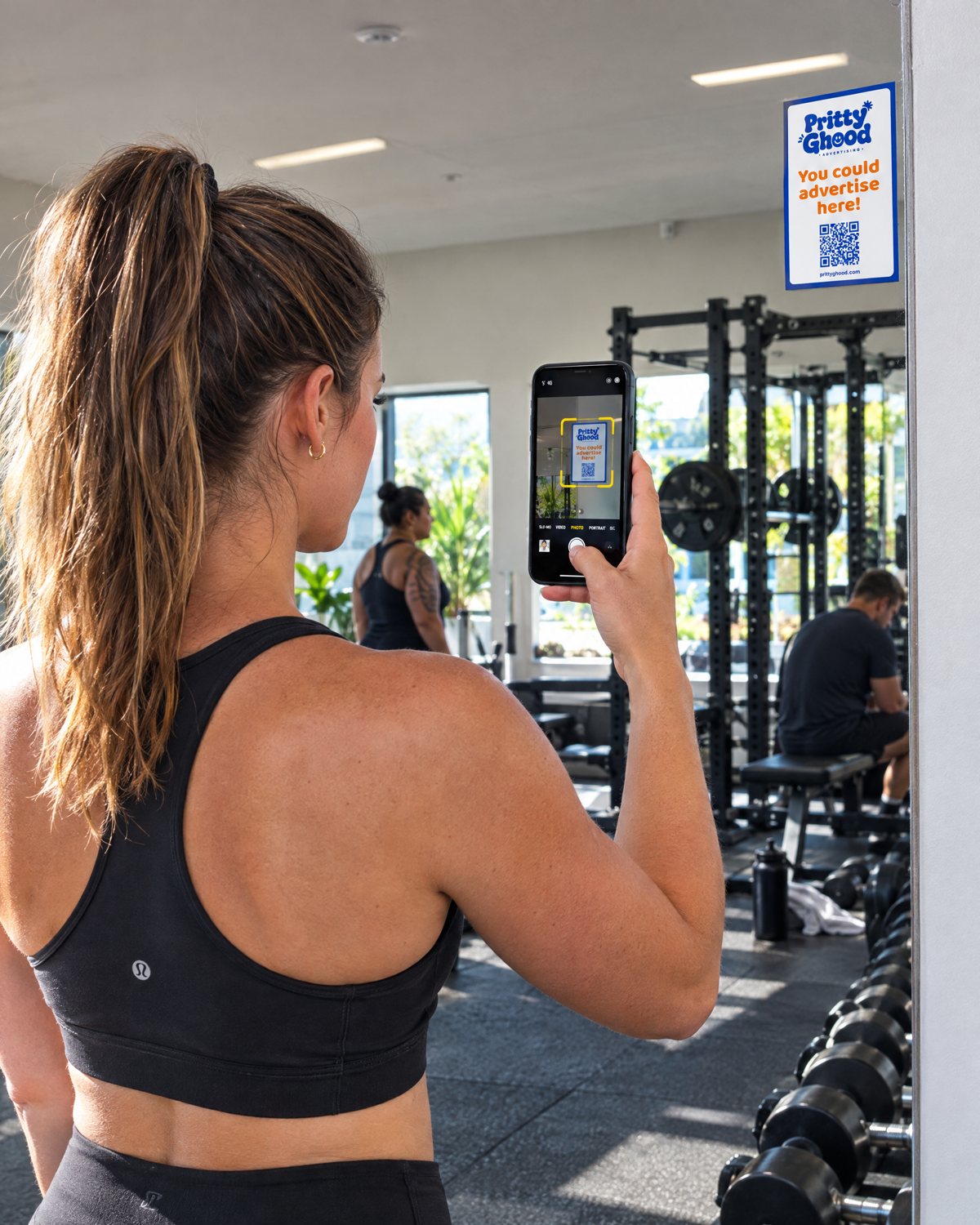 A gym member scanning the QR code on a Pritty Ghood ad on the mirror with her phone