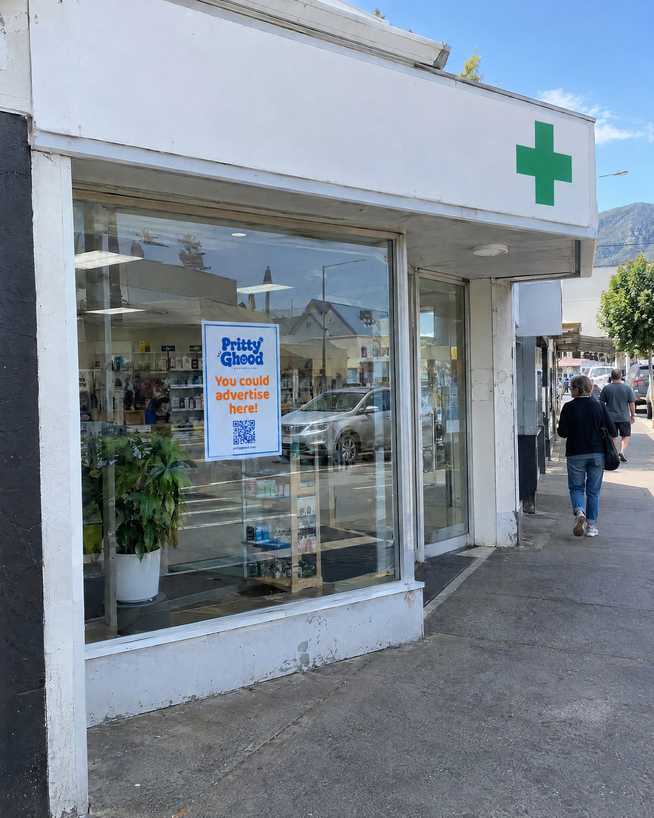 A pharmacy shopfront with a Pritty Ghood poster inside the window